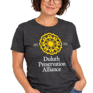 A woman wearing a charcoal gray t-shirt with a yellow and white Duluth Preservation Alliance logo.